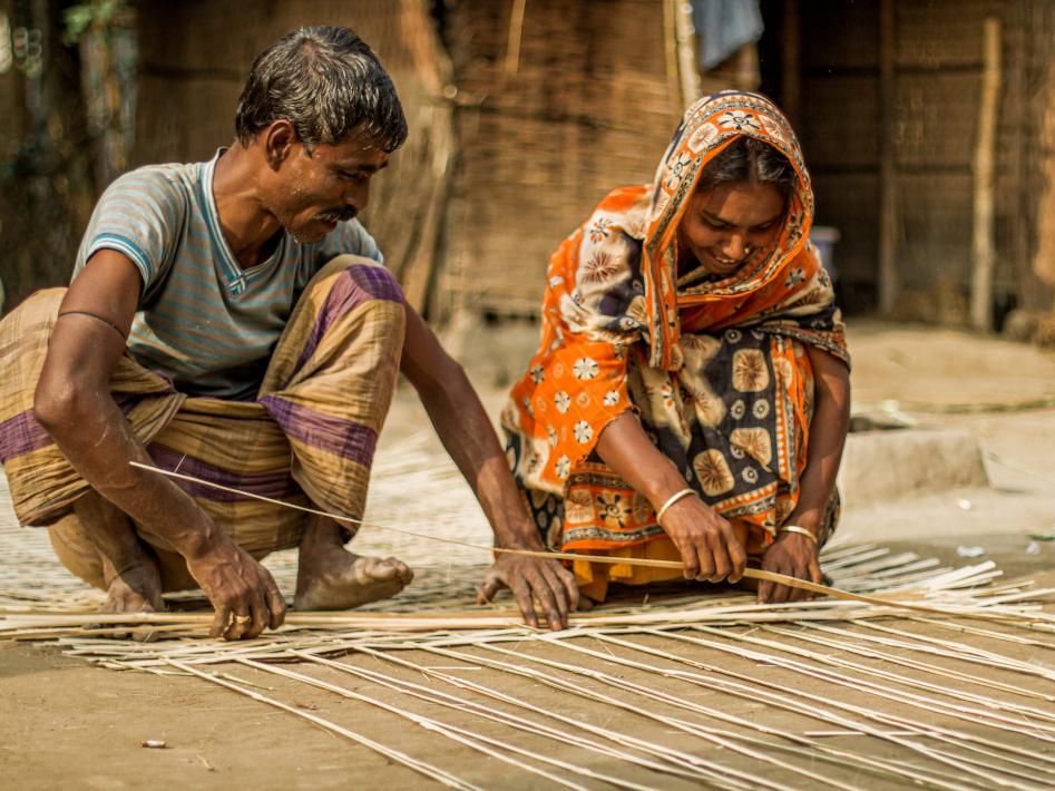Korgflätning pågår. En kvinna och en man från Bangladesh flätar en korg tillsammans