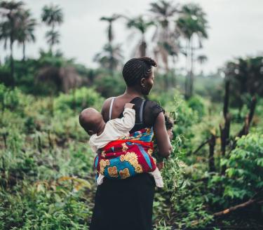 A walk in the rain forest in Sierra Leone. A woman take a walk with a baby on here back in the rain forest in Sierra Leone.