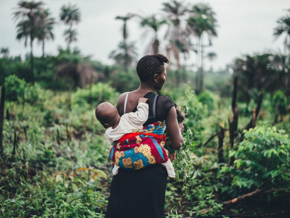A walk in the rain forest in Sierra Leone. A woman take a walk with a baby on here back in the rain forest in Sierra Leone.